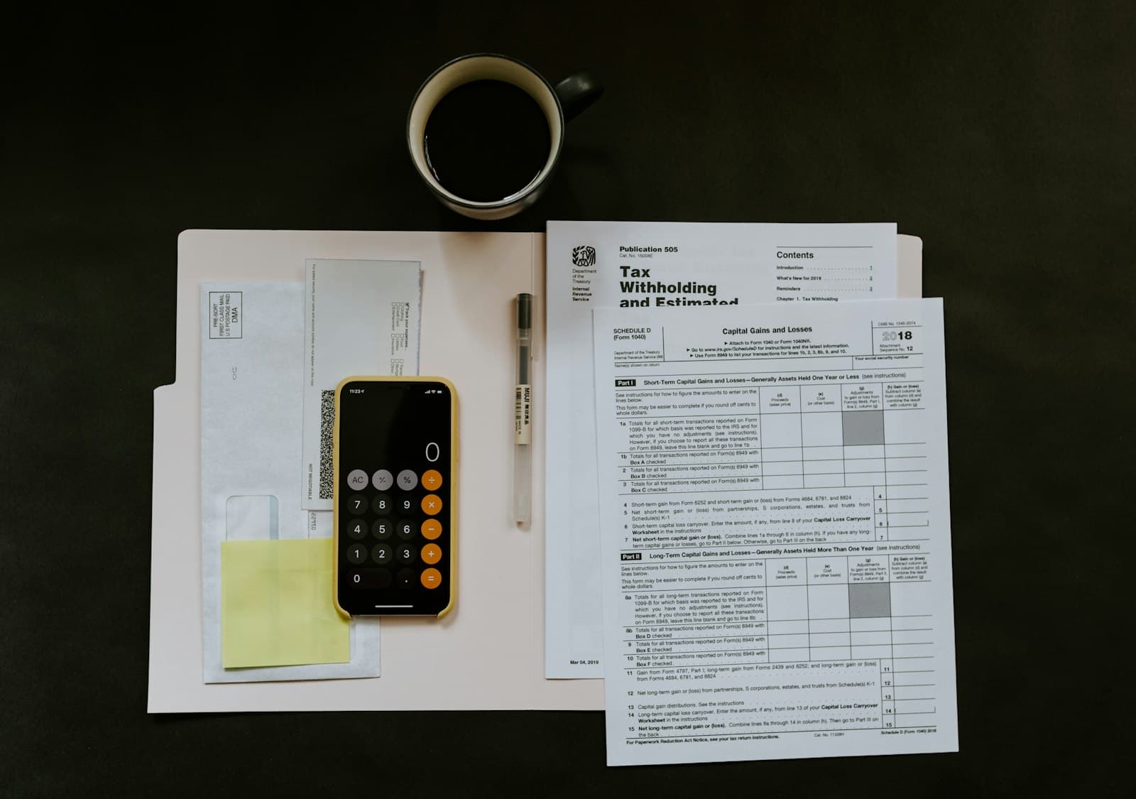 A tax withholding form next to a calculator and a cup of coffee on a desk
