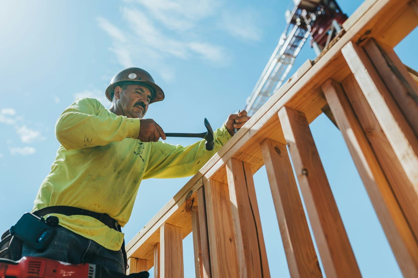 A construction worker in a hard hat hammering a wooden frame on site