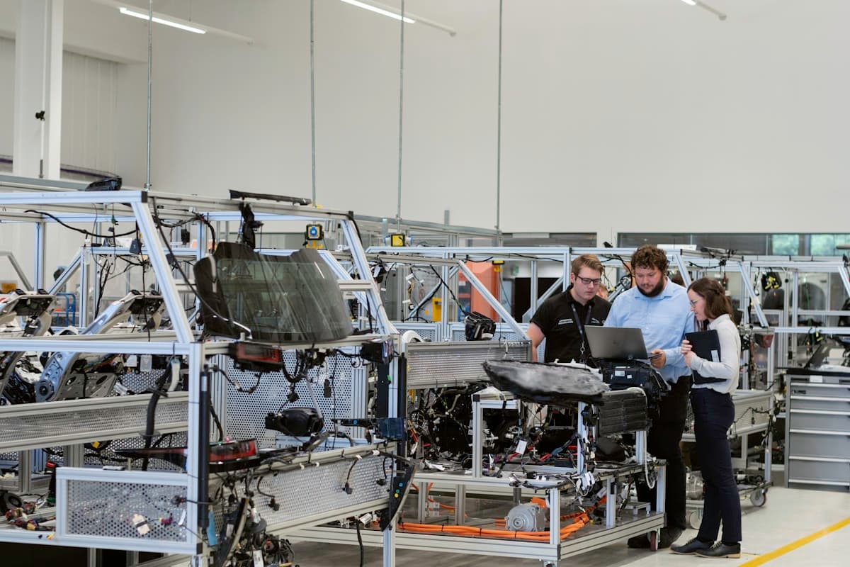 Factory engineers reviewing data on a laptop next to an assembly line
