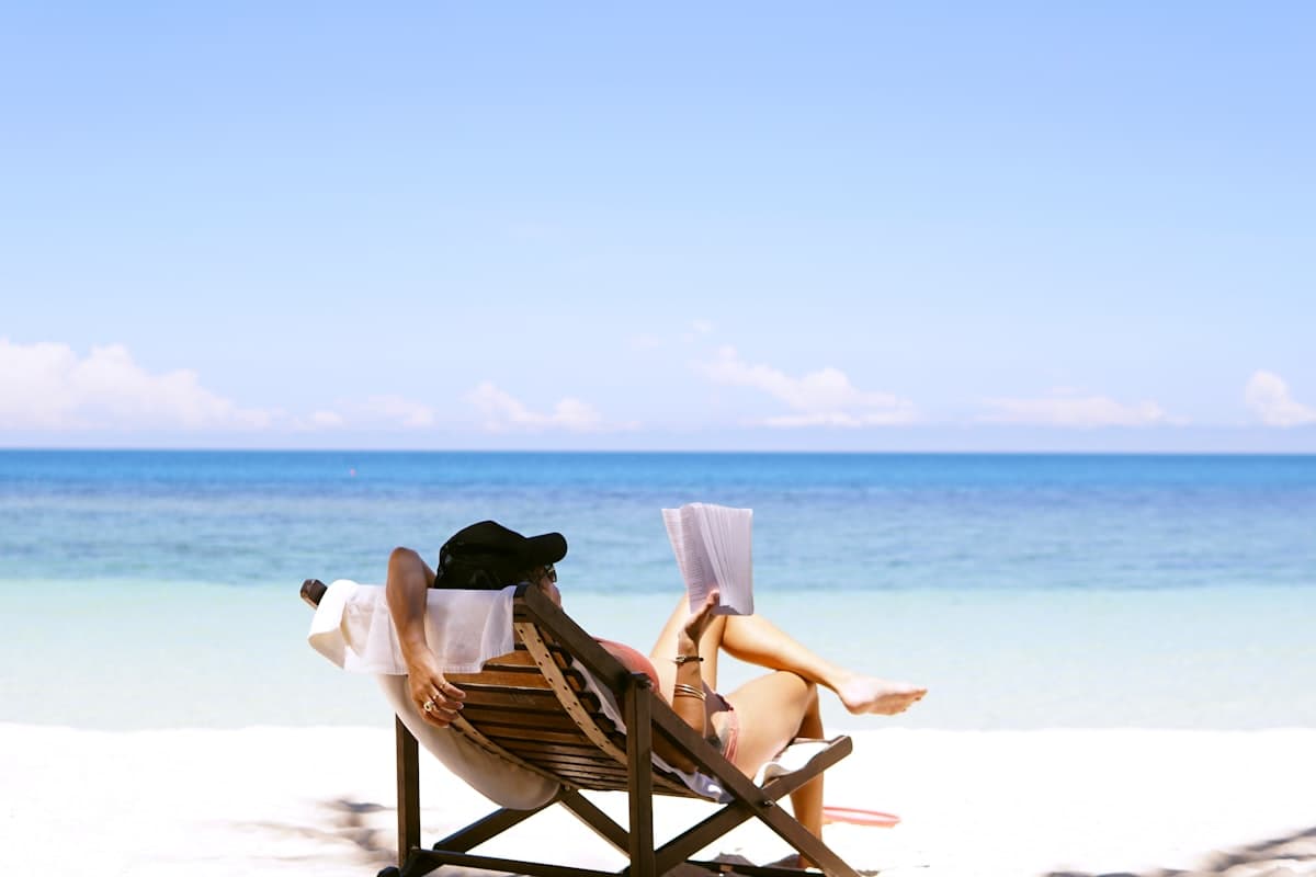 A person relaxing on a beach chair reading a book, representing time off actually being used