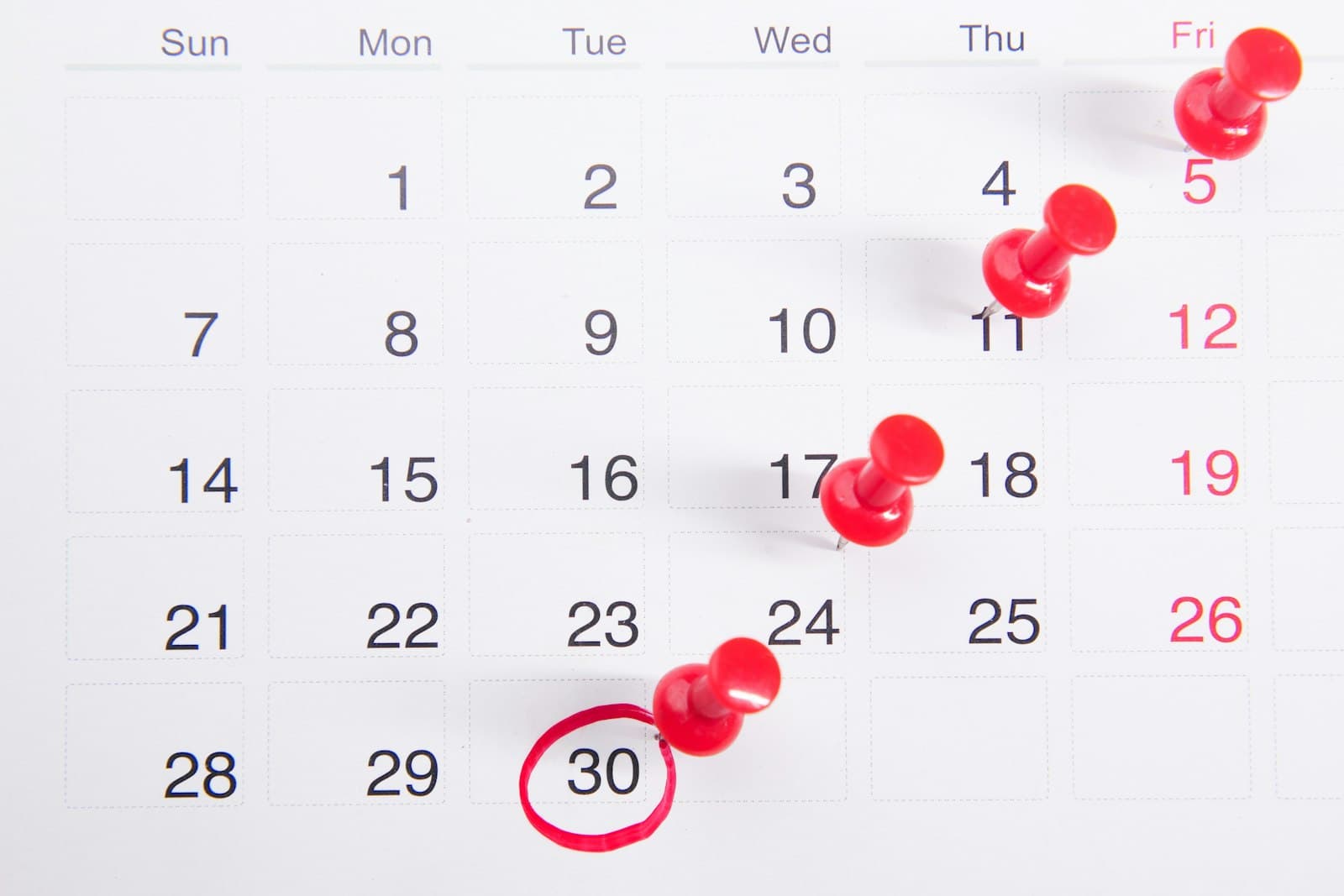 A wall calendar with red pins marking upcoming dates, representing leave planning