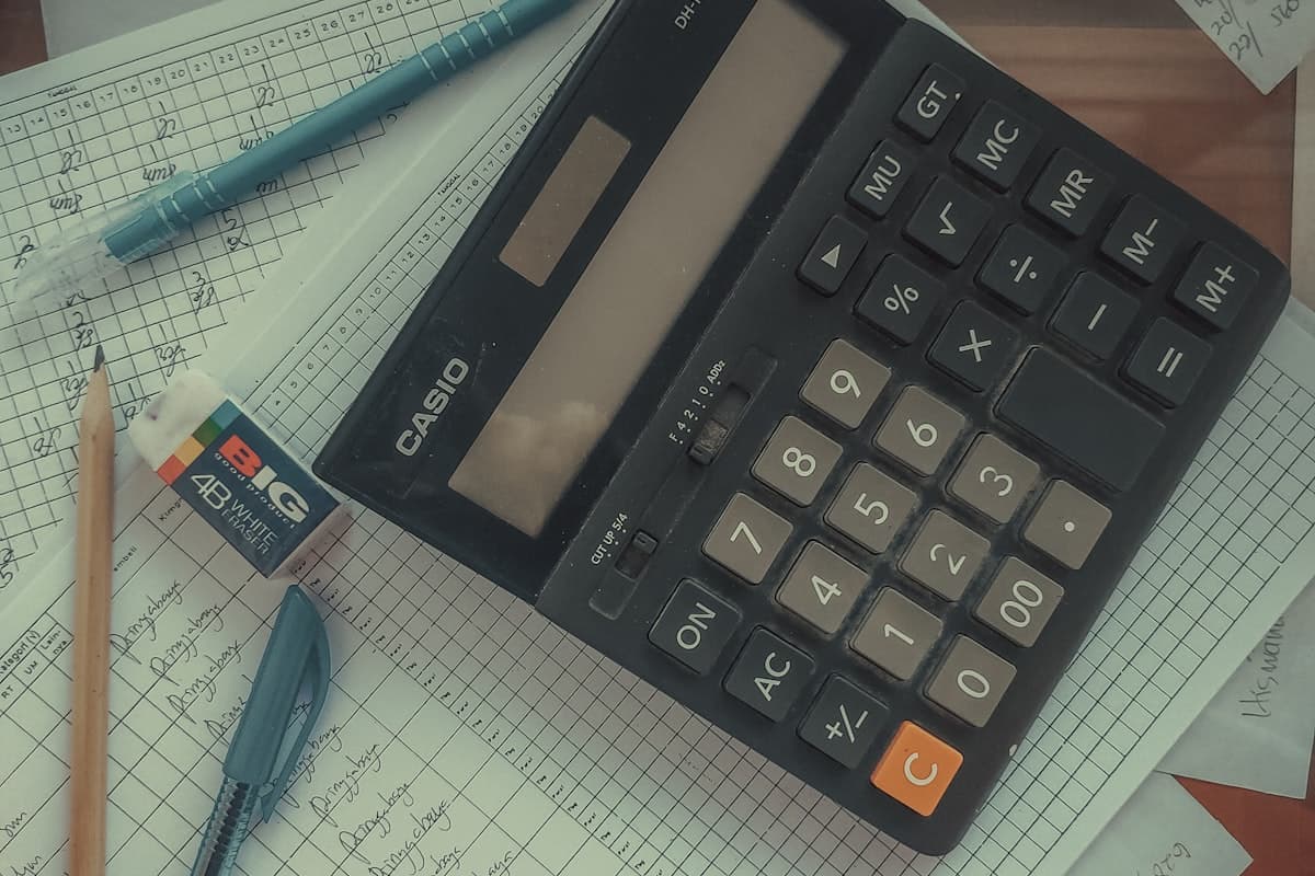 A calculator resting on a handwritten ledger with columns of numbers