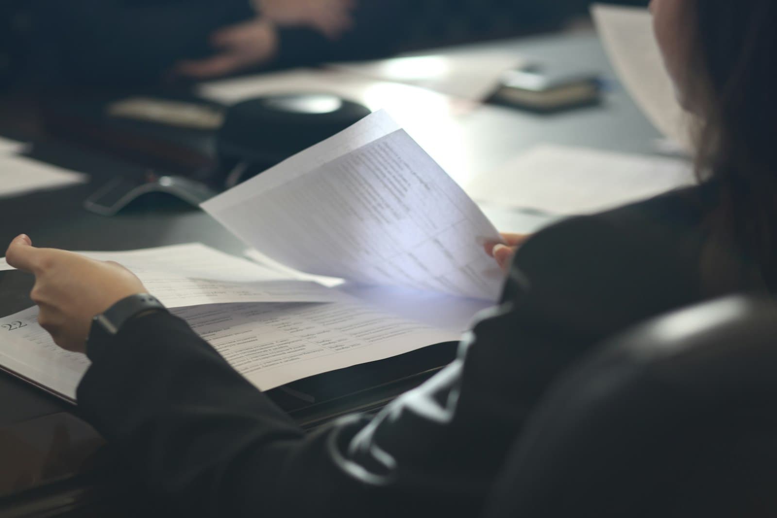 An HR professional reviewing employee documents at a meeting table