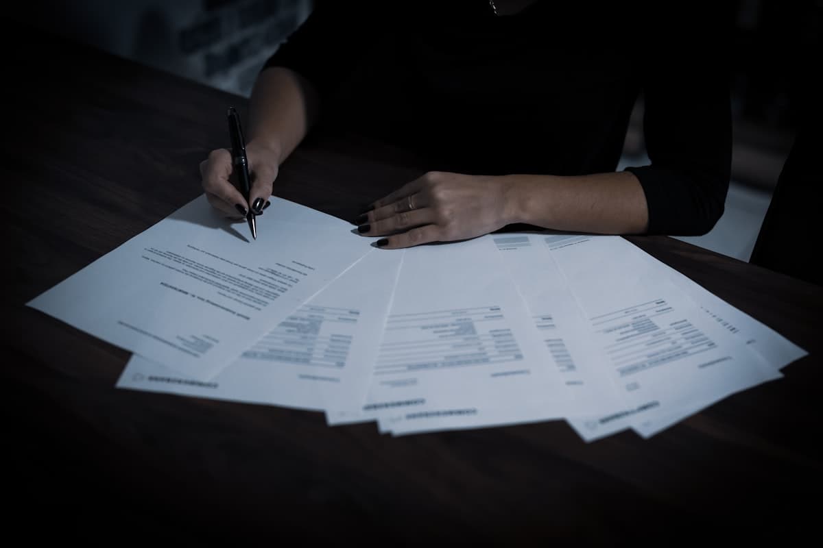 A hand signing and reviewing HR documents on a desk