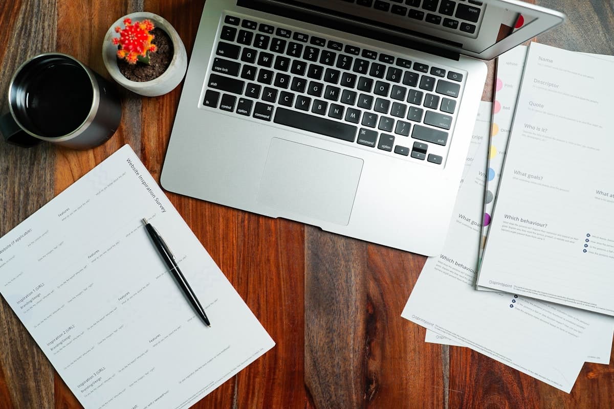 A laptop and onboarding paperwork laid out on a desk, ready for a new hire