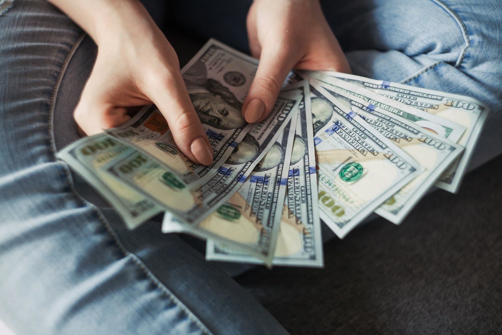 Close-up of hands counting a fan of banknotes, representing salary and payroll processing