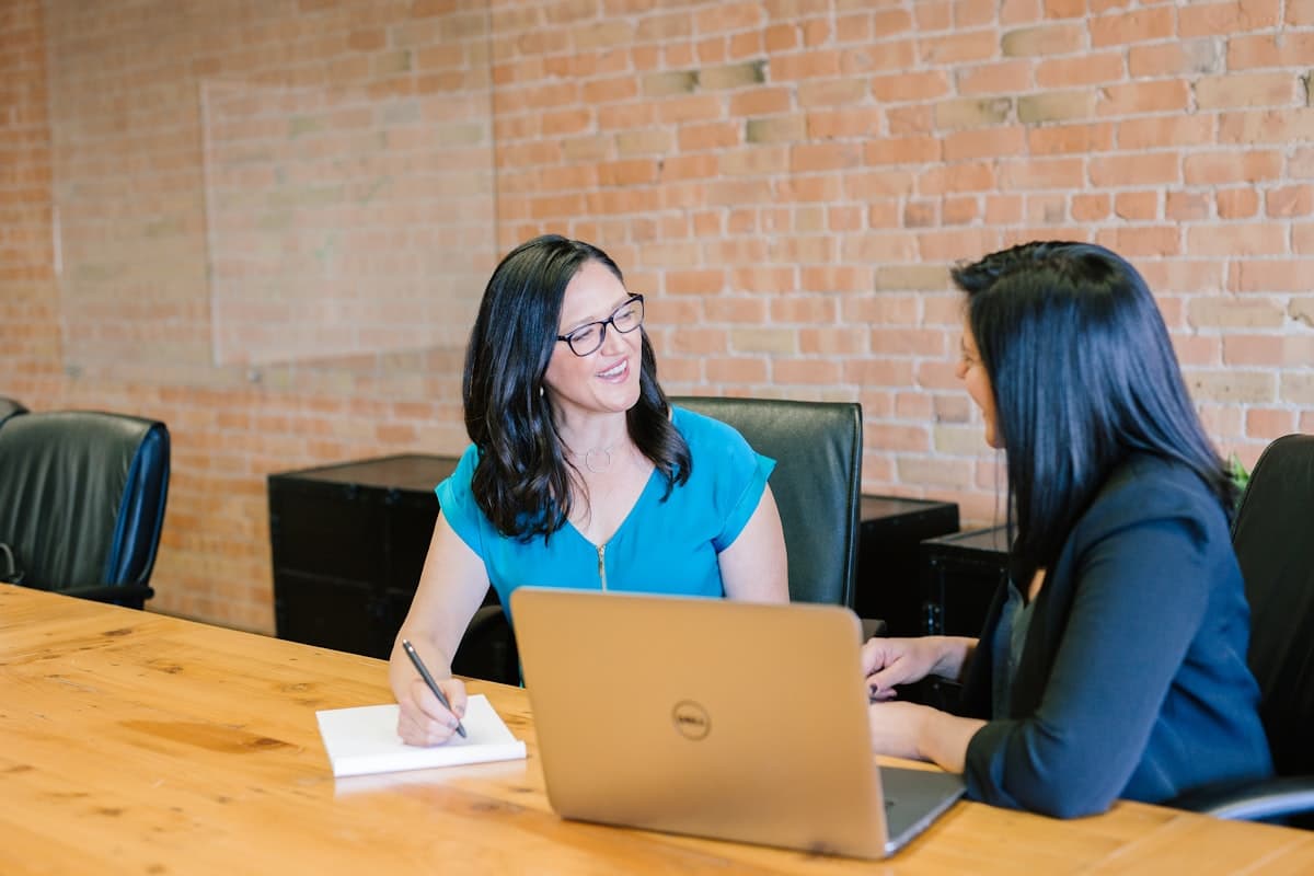 Two colleagues reviewing figures together on a laptop at a meeting table